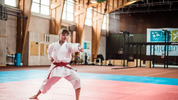Karateka harjoittelee tatamilla urheiluhallissa.