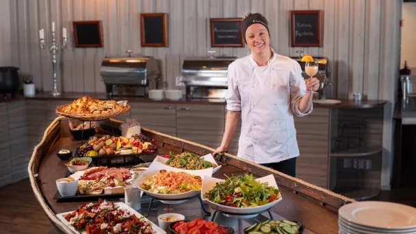 Kokki seisoo seisovassa pöydässä täynnä erilaisia ruokia.