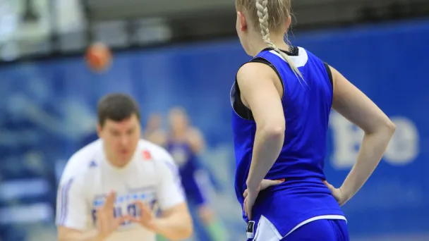 Basketball player in blue listens to coach indoors.