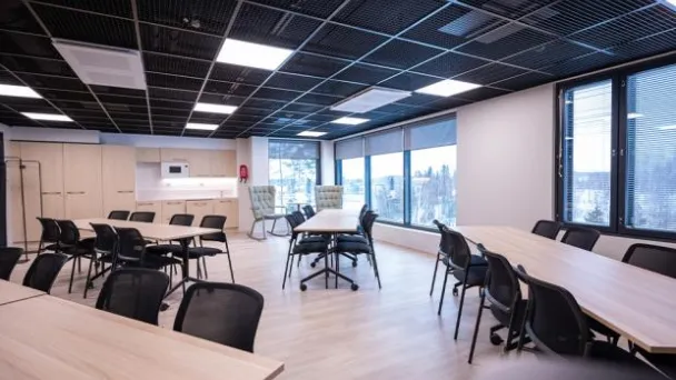 Moderni toimistotila, ikkunat, pöydät ja tuolit.