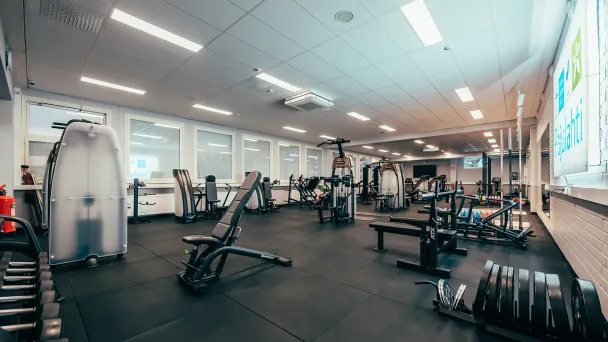 Kuntosali, jossa kuntolaitteita ja vapaita painoja.