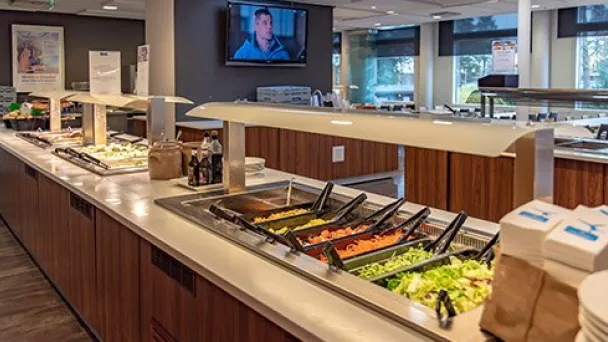 Buffet-pöytä salaattilinjoilla, ravintolasali taustalla.