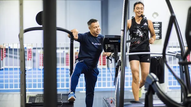 Personal trainer kannustaa naista kuntosalilla juoksemisen aikana.