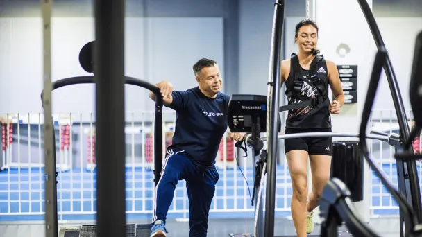 Personal trainer kannustaa naista kuntosalilla juoksemisen aikana.