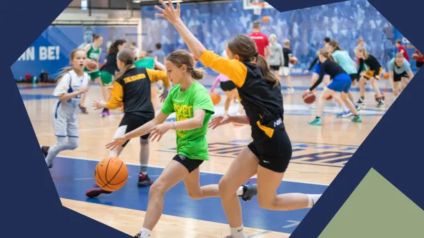 Koripallopeli sisätiloissa, lapset juoksevat pallon kanssa.