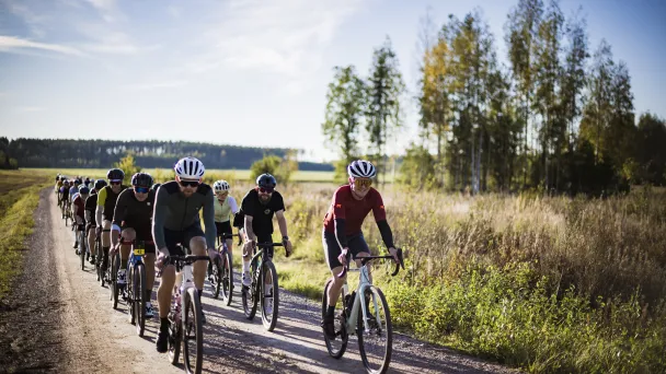 Gravel-pyöräilijät maaseudun soratiellä aurinkoisessa säässä.