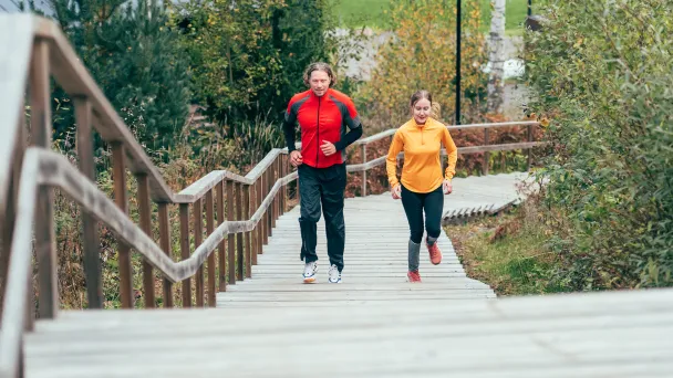Mies ja nainen hölkkäävät Kisakallion villamäen kuntoportaita.