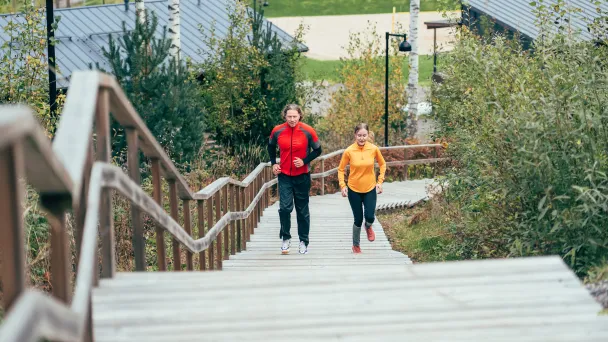Mies ja nainen hölkkäävät Kisakallion kuntoportaita.