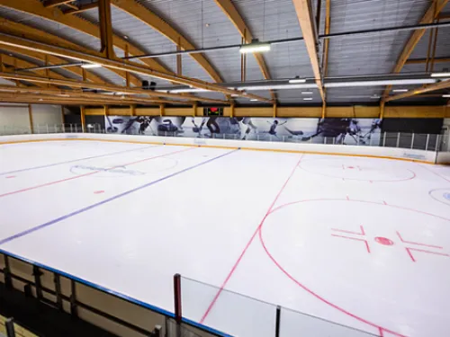 Indoor ice hockey rink with painted lines and wooden ceiling.