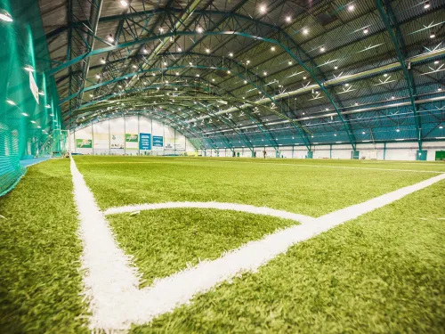 Indoor soccer field with artificial turf and overhead lighting.