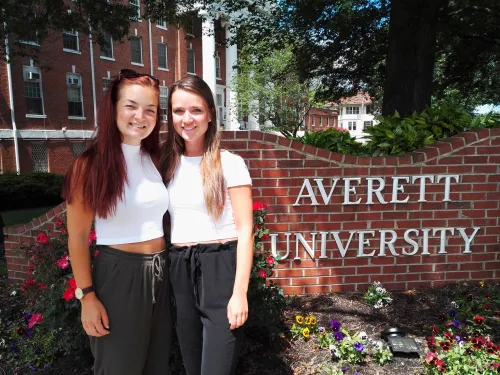 Kaksi naista hymyilee Averett University -kyltin edessä.