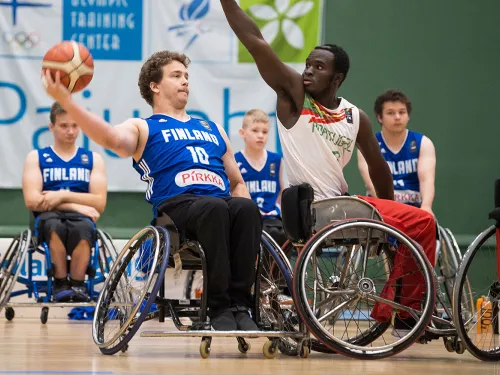 Wheelchair basketball game, players reaching for a ball.