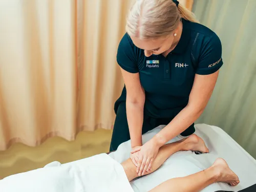 Hieroja hieroo asiakkaan jalkaa hoitohuoneessa.