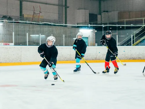 Jääkiekkoilijat pelaavat jääkiekkokaukalossa.