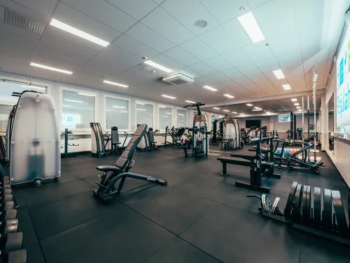 Tyhjä kuntosali, jossa on kuntolaitteita ja painoja.