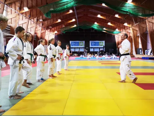 Judo-opettaja ohjaa opiskelijoita tatamilla sisätiloissa.