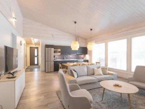 Villa Kaarinan avara olohuone, vaaleat sävyt, moderni keittiö taustalla.