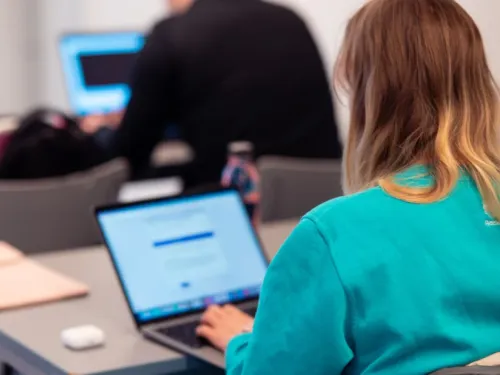 Nainen työskentelee kannettavalla tietokoneella luokassa.