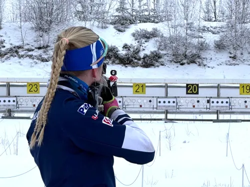 Hiihtäjä tähtää ampumahiihtoradalla lumisessa maisemassa.