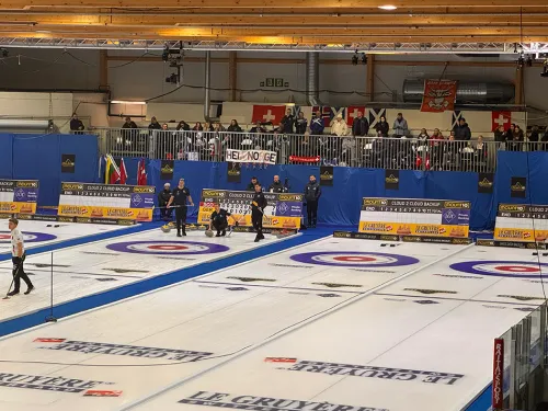 Curling-kilpailu sisätiloissa, useita kenttiä, katsomossa yleisöä.