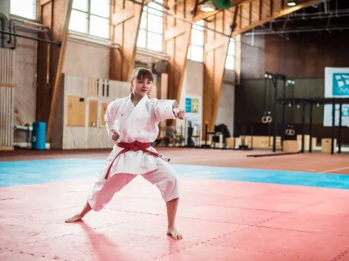 Karateka harjoittelee tatamilla urheiluhallissa.