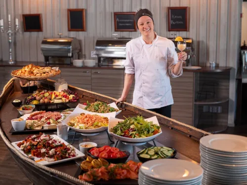 Kokki seisoo seisovassa pöydässä täynnä erilaisia ruokia.