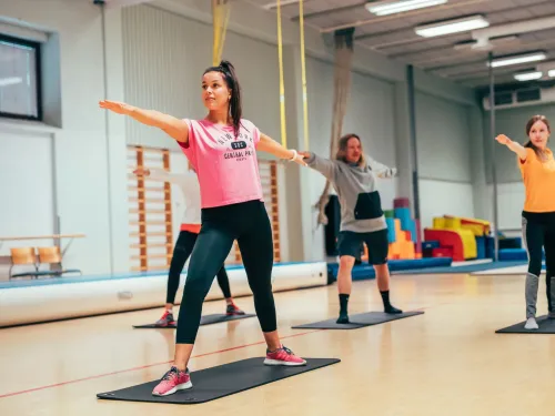 Joogaajat venyttelevät kirkkaassa liikuntasalissa.