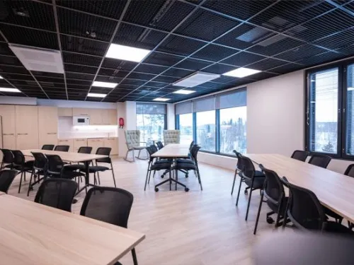 Moderni toimistotila, ikkunat, pöydät ja tuolit.