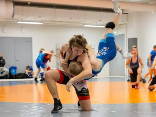 Nuoria painijoita harjoittelemassa sisätilassa. Yksi nostettu ilmaan.