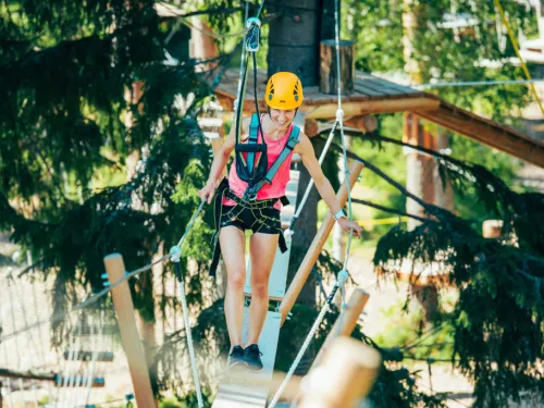 Nainen seikkailupuistossa kiipeilyradalla, kypärä päässä.