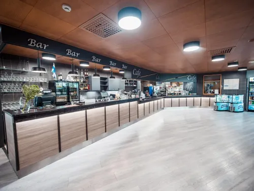 Moderni kahvila, puupaneelein koristeltu tiski ja valaistut hyllyt.