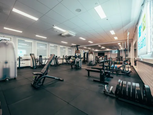 Kuntosali, jossa kuntolaitteita ja vapaita painoja.