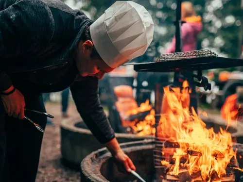 Keittiömestari kokkaa ulkona avotulella.