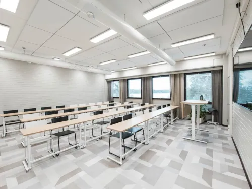 Valoisa luokkahuone, jossa on riveittäin pöytiä ja tuoleja.