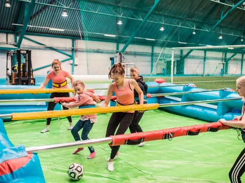 Aikuiset ja lapset pelaavat ihmisfutista sisähallissa.