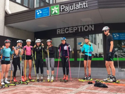 Rullasuksia käyttävä ryhmä nuoria seisoo vastaanottorakennuksen edessä.