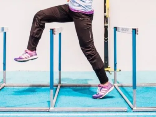 Juoksija ylittää esteitä sisäradalla, jalat ilmassa.