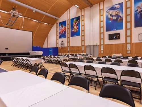 Tapahtumasali, jossa valkoisia pöytiä ja mustia tuoleja.