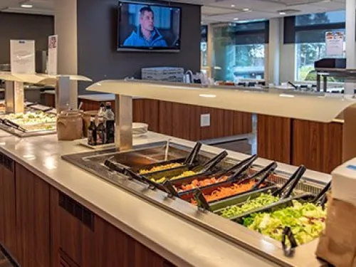 Buffet-pöytä salaattilinjoilla, ravintolasali taustalla.