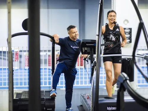 Personal trainer kannustaa naista kuntosalilla juoksemisen aikana.
