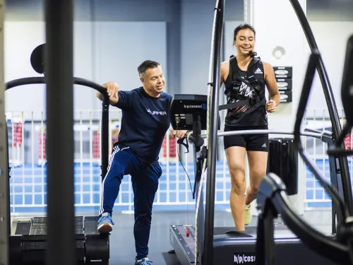 Personal trainer kannustaa naista kuntosalilla juoksemisen aikana.