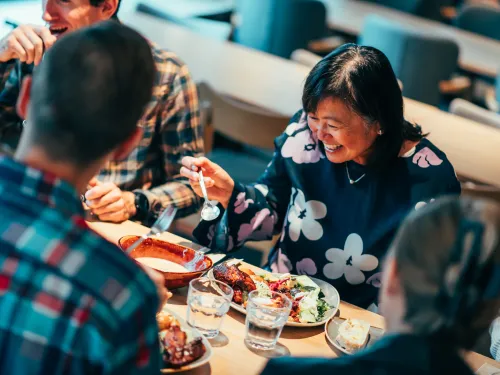 Ihmiset nauttivat ateriasta ravintolassa ja hymyilevät.