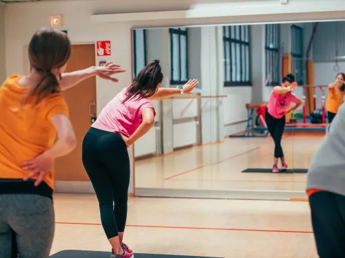 Naiset tekevät ryhmäliikuntaa kuntosalilla.