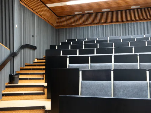 Auditorion tyhjät istuimet valkoisten katto- ja seinäpaneelien alla.