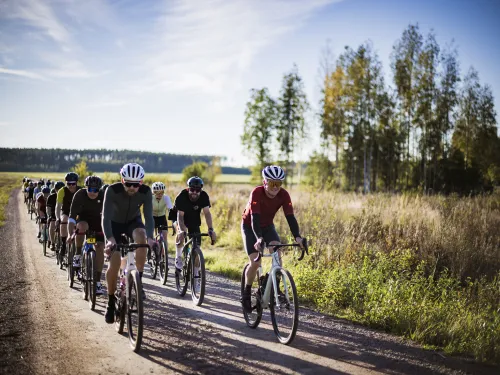 Gravel-pyöräilijät maaseudun soratiellä aurinkoisessa säässä.