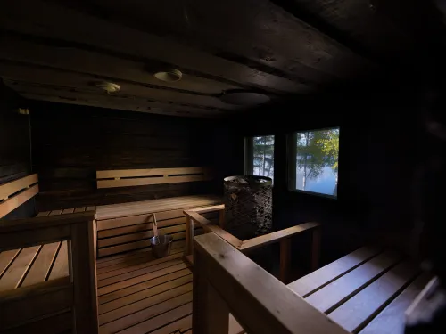 Hämyinen saunatila. Ikkunasta näkyy sininen järvi ja puita. 