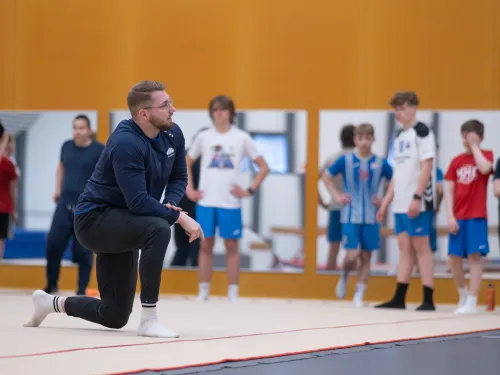 Urheilun asiantuntija kouluttamassa fysiikkaharjoitteita yläkoululeirityksen oppilaille