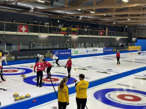 Curling-ottelu hallissa, pelaajat keltaisissa ja punaisissa paidoissa. Yleisö katsomossa.