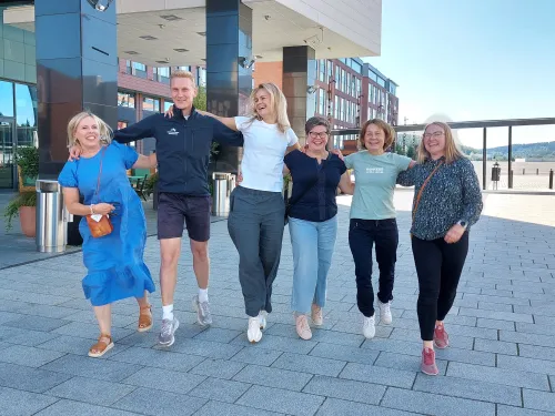 Iloinen ryhmä kuusi ihmistä kävelee yhdessä ulkona.