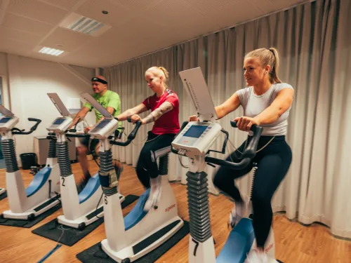 Kolme ihmistä kuntotestissä pyöräergossa